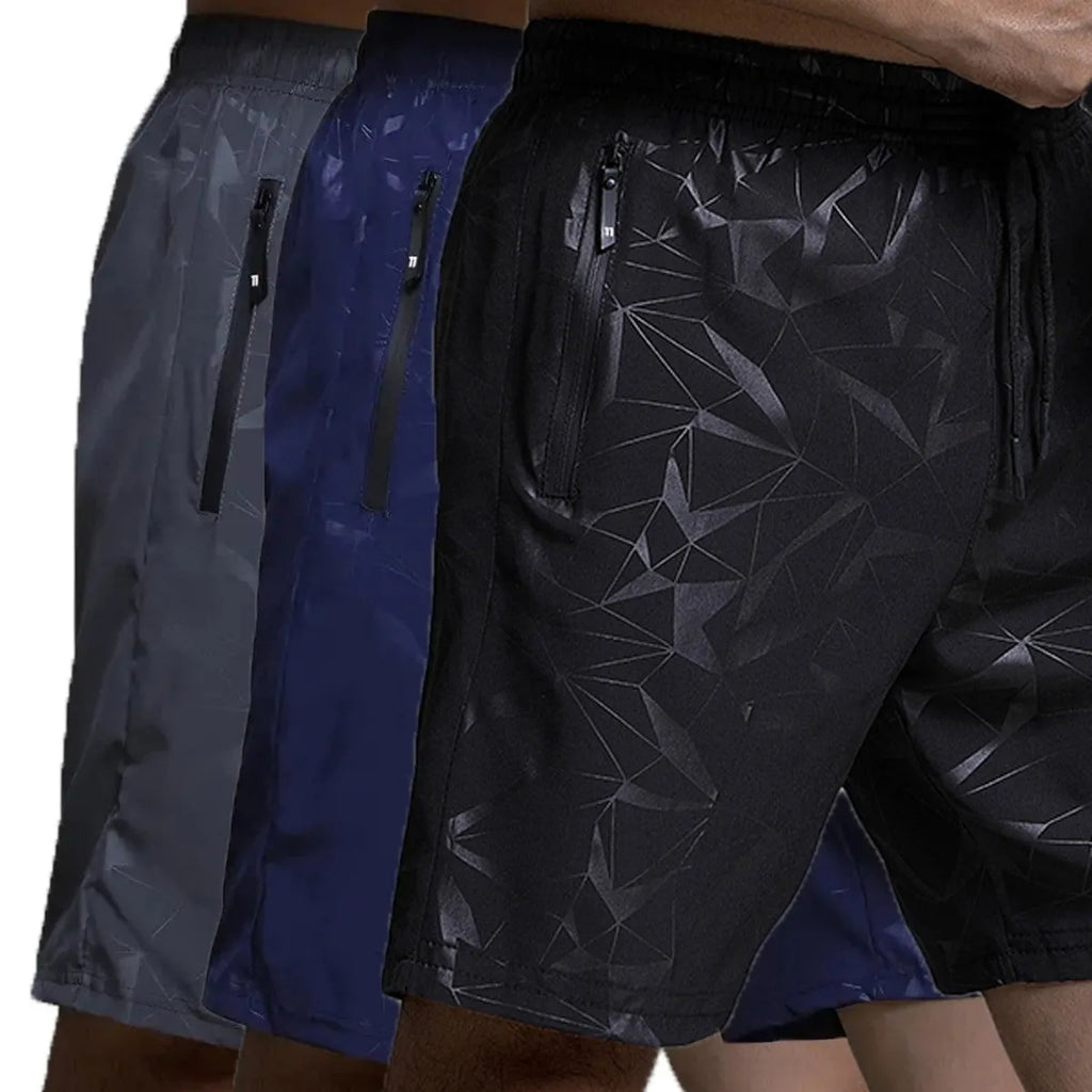 Man wearing loose-fit black printed sports shorts with an elasticated waist on a beach.