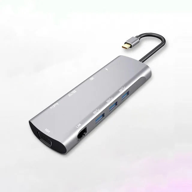 Grey aluminium USB-C docking station with HDMI, VGA, USB 3.0, and PD charge ports on a desk.
