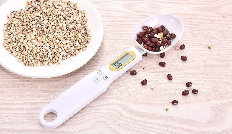 Black electronic digital scale with integrated measuring spoon showing weight display.