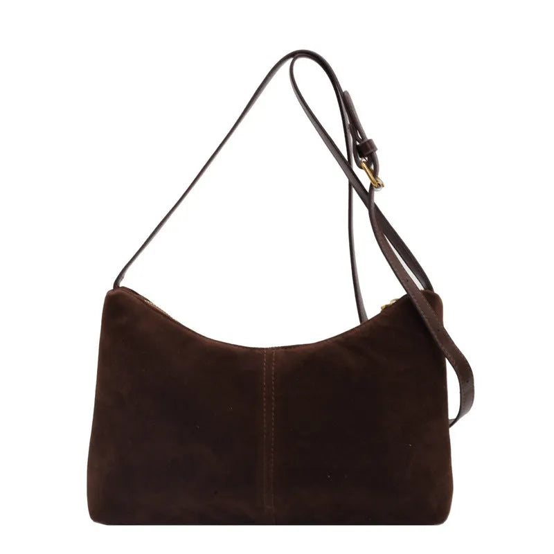 Retro brown suede underarm bucket bag with visible sewing line detail on a woman's shoulder during commute