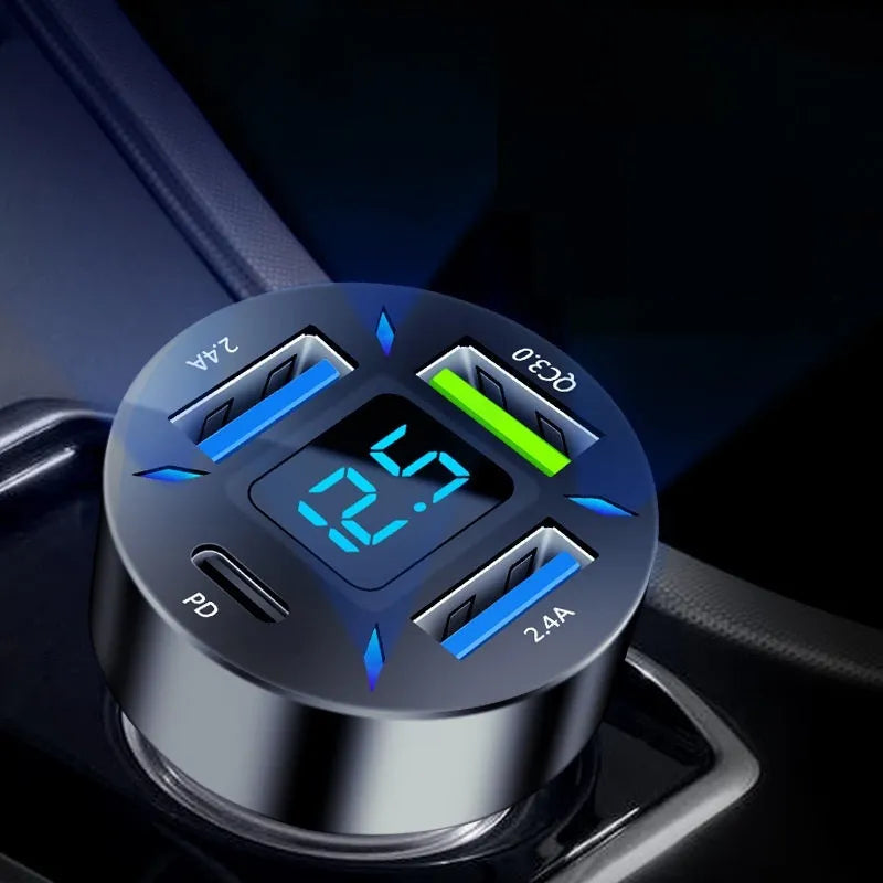 Black four-port USB car charger with LED voltage display plugged into a car socket.