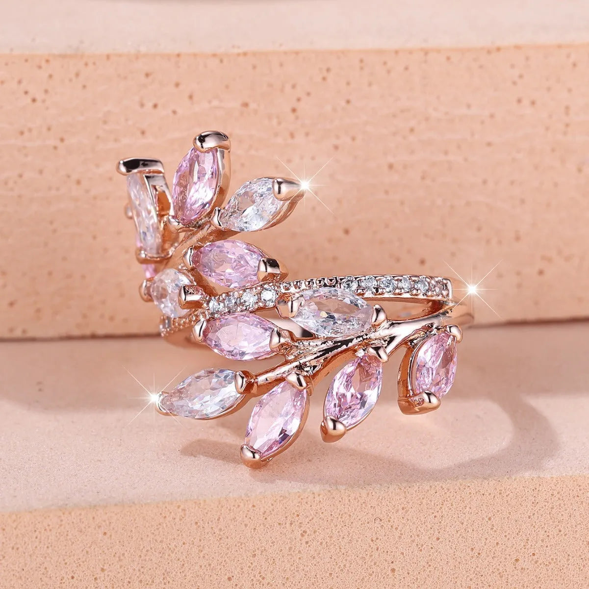Adjustable copper leaf ring with a central zircon stone on a finger, showing rose gold and platinum colour options.