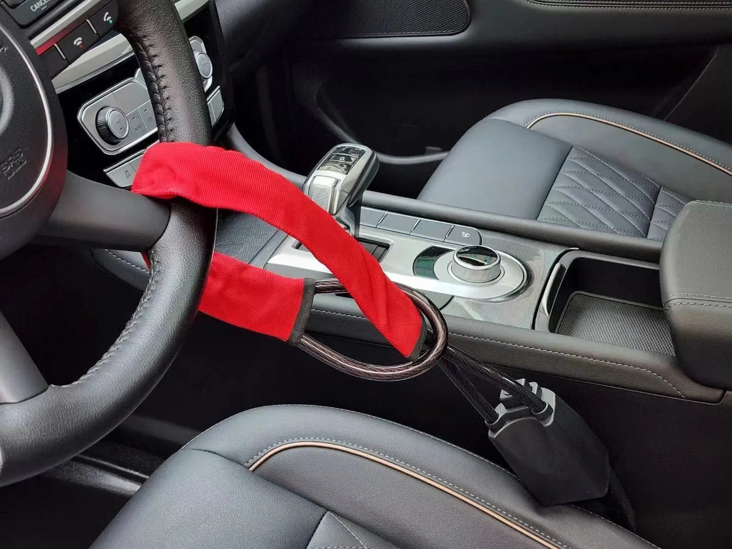 Red iron car steering wheel lock with wire rope for General Motors vehicles on a steering wheel.