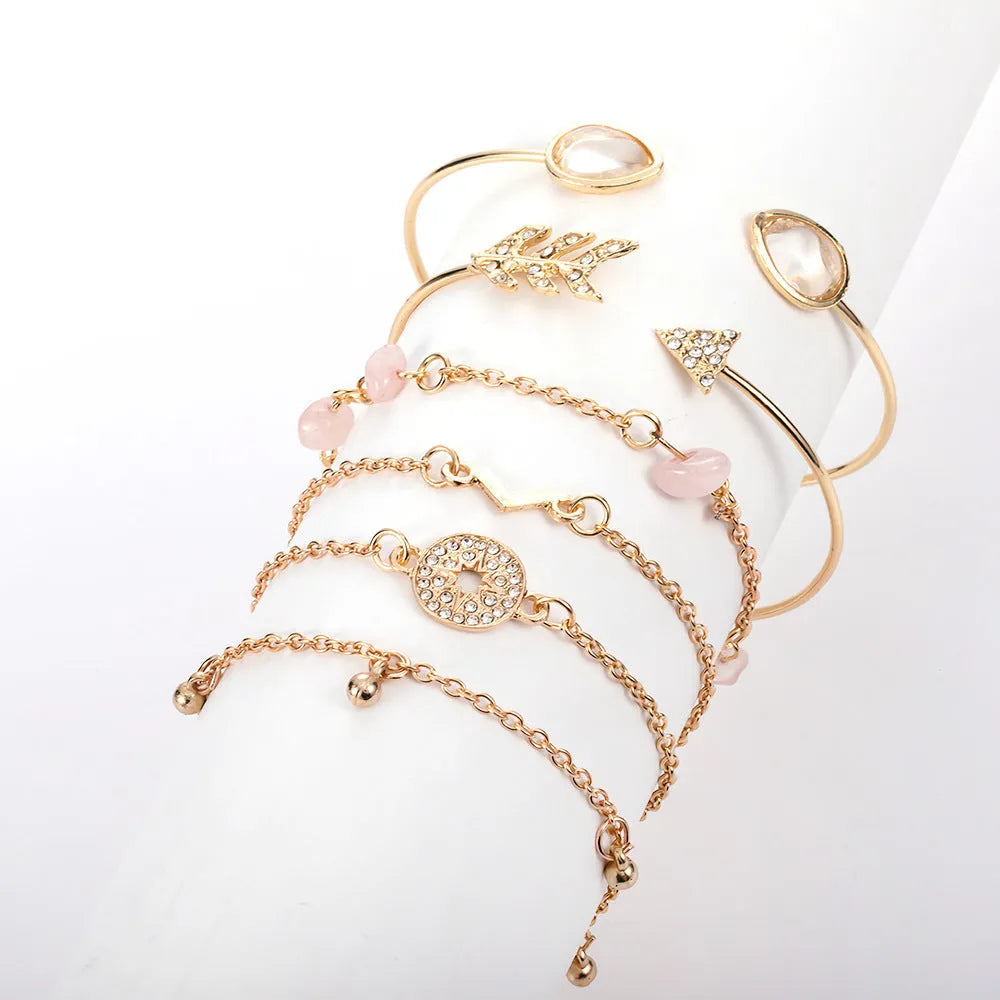 Set of six gold bracelets with arrow, water drop, and V shapes featuring spot drill detail.