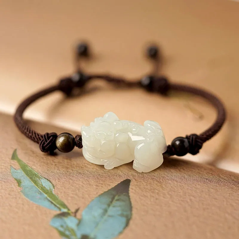 Close-up of a brown and black braided rope bracelet with a central Hetian jade bead on a wrist.