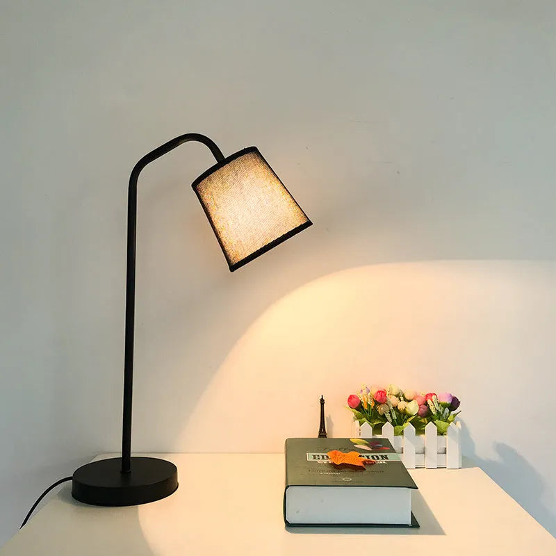 A simple modern Nordic style LED desk lamp with a dimmer switch on a desk.
