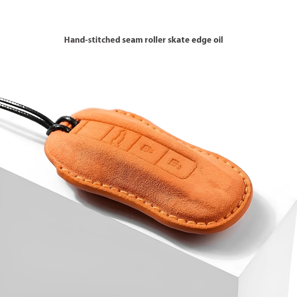 Suede car key cover in cement grey, dark green, light grey, and orange colour options on a plain background.