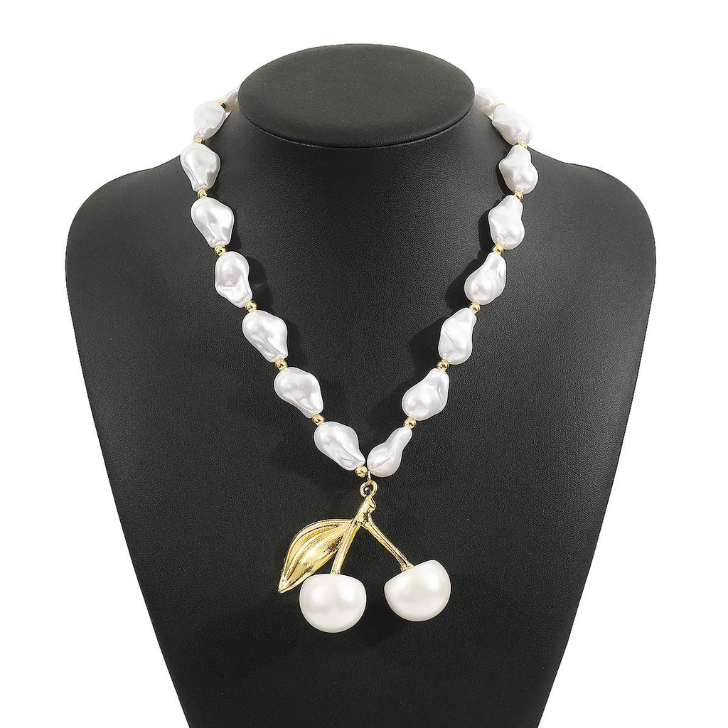 Gold-tone irregular cherry fruit pendant on an adjustable string of white imitation pearls necklace.