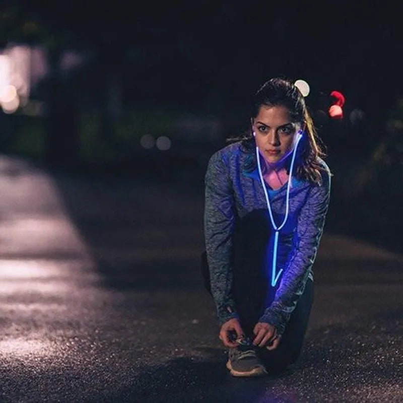 Blue, green, and pink LED earphones with glowing cables next to a smartphone, showcasing their music-reactive light feature.