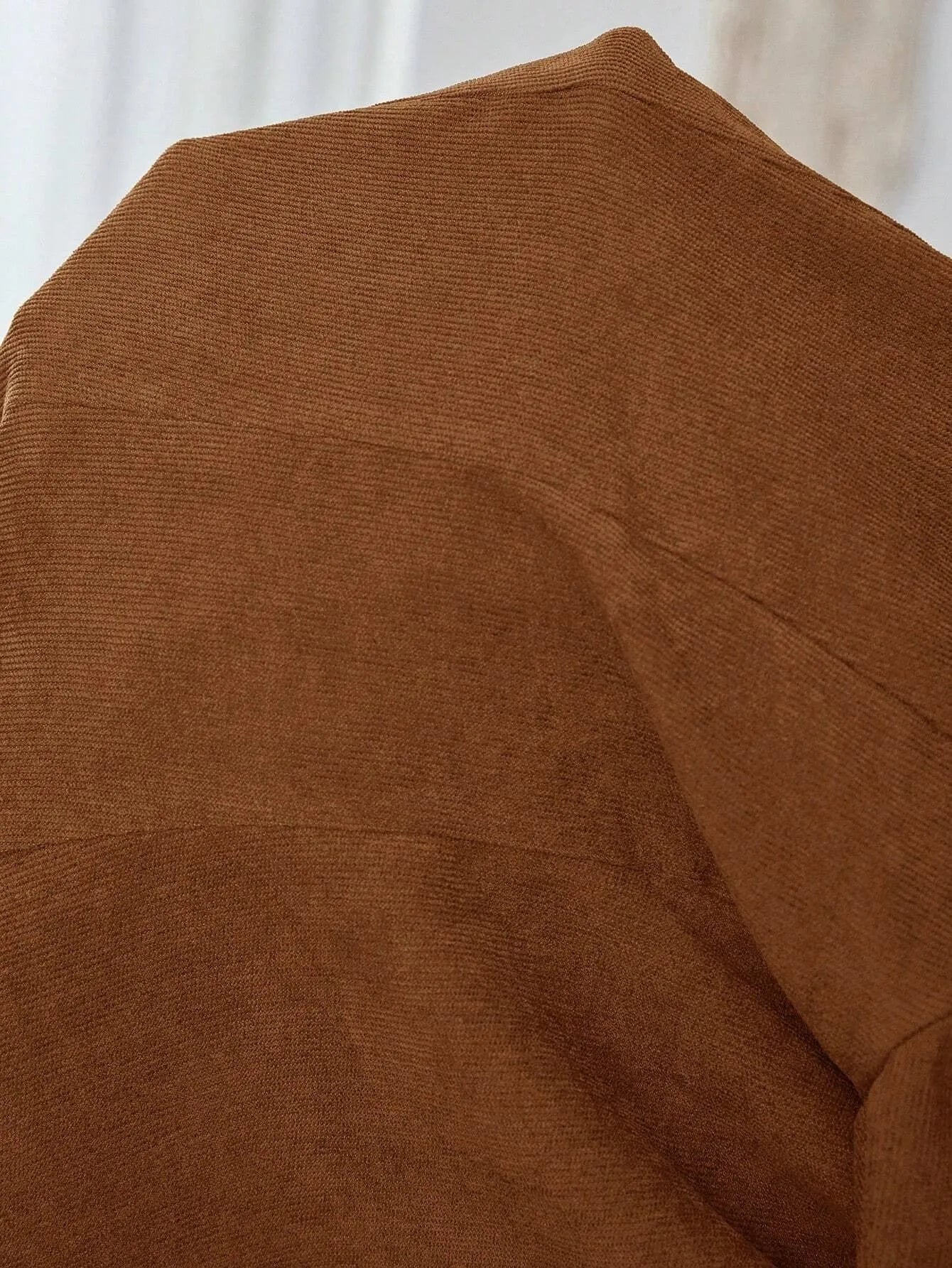 Brown single-breasted suit coat with lapel and long sleeves on a hanger.