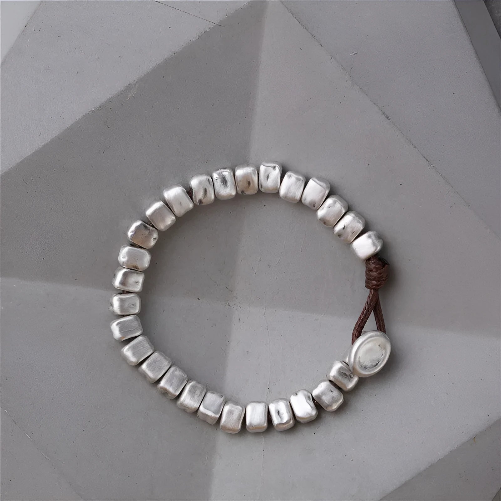 Handmade women's bracelet with an irregular silver square pendant on a wooden elastic band.