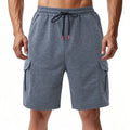 Men's loose-fit grey terry fabric cargo shorts with multiple pockets on a plain background.