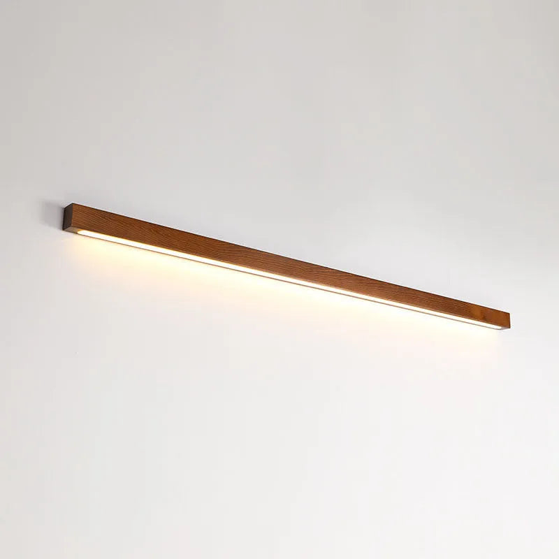 Walnut colour long wooden strip wall lamp with integrated LED lighting mounted on a wall.