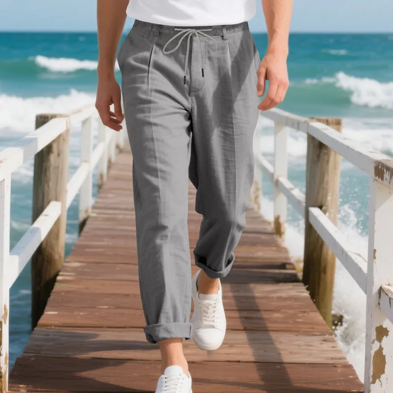 Man wearing light khaki linen casual trousers with a drawstring waist and straight-leg fit.
