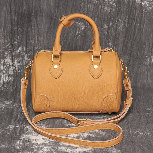 Brown yellow cowhide leather Boston bag with single shoulder strap, showing cylindrical shape and open outer pocket.