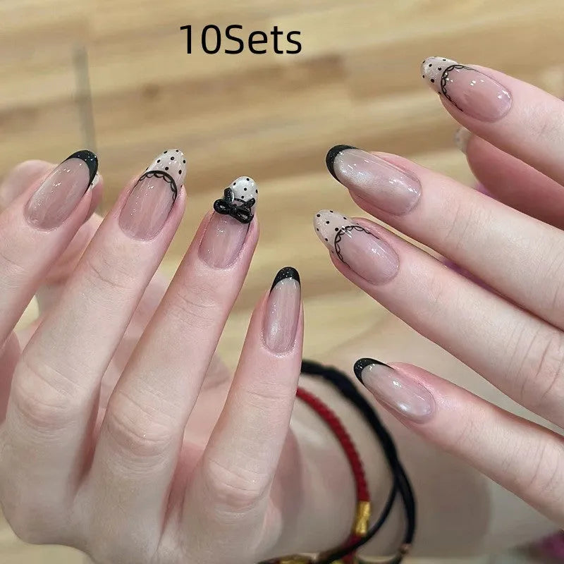 Set of medium-length coffin-shaped false nails with French manicure glitter tips and rhinestone decorations.