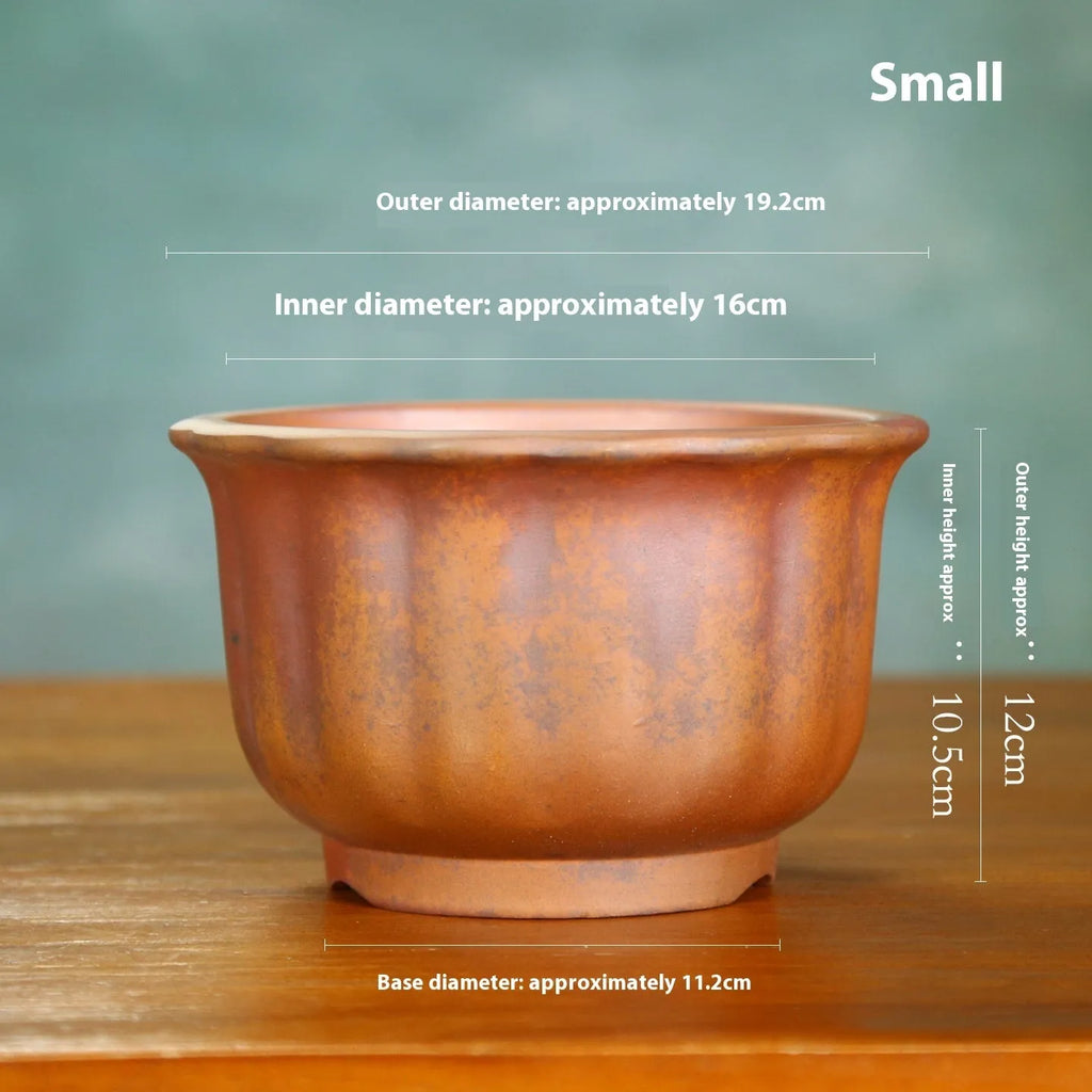Antique carved ceramic flower pot with wood burning finish on a wooden table.