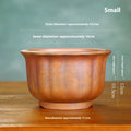 Antique carved ceramic flower pot with wood burning finish on a wooden table.