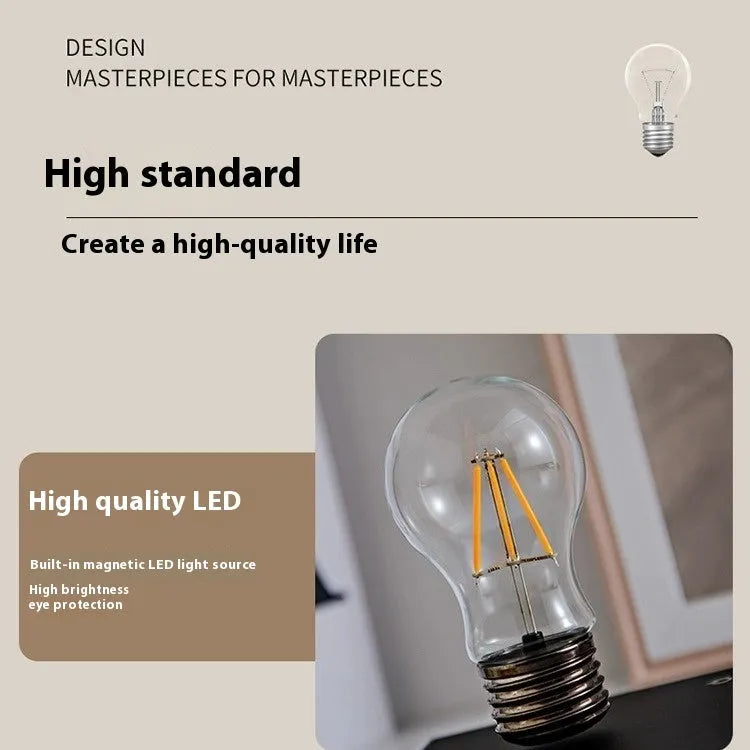 Small black suspension bulb night lamp with an iron art base on a wooden desk.
