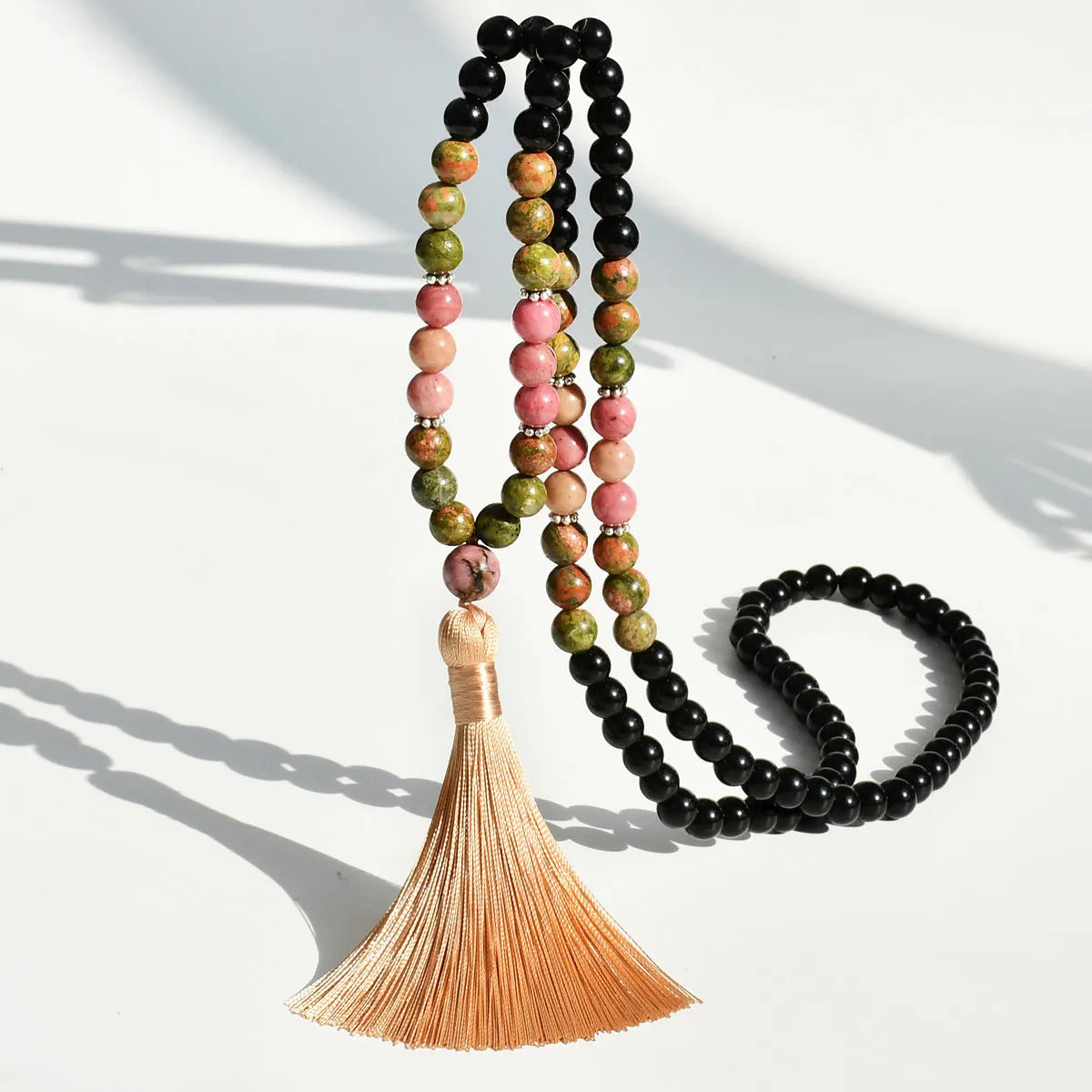A long bohemian-style necklace with a geometric mixed gemstone pendant and a coloured tassel on a ball bead chain.