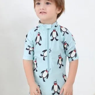 Boy in penguin print long sleeve one-piece swimsuit and matching swimming cap