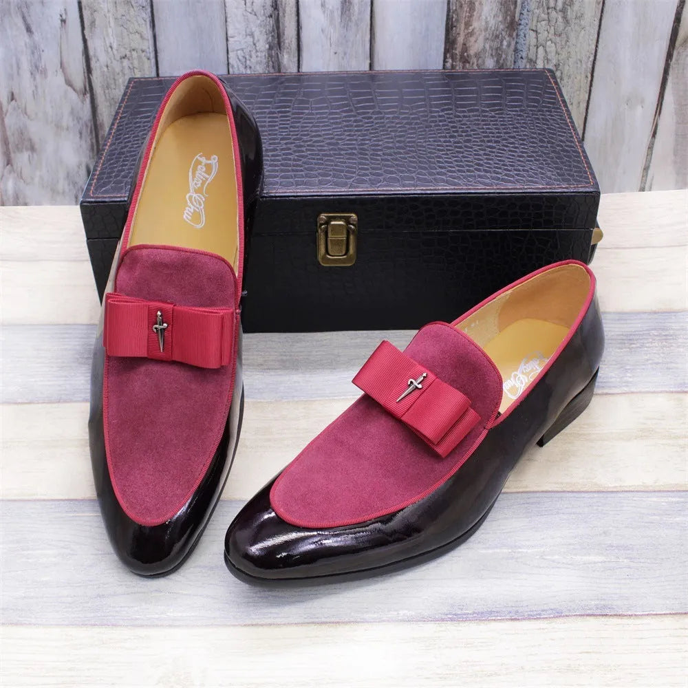 Men's black and brown tassel loafers with a matte and patent leather upper on a wooden floor.
