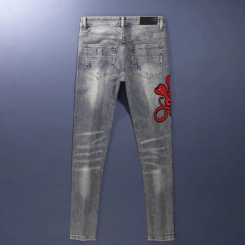 Men's slim fit washed-out denim jeans with hole patches and embroidery on a mid waist.