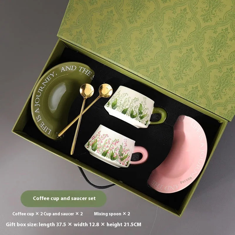 Ceramic coffee cup and saucer set for two with stirring spoons in couple's cup design.