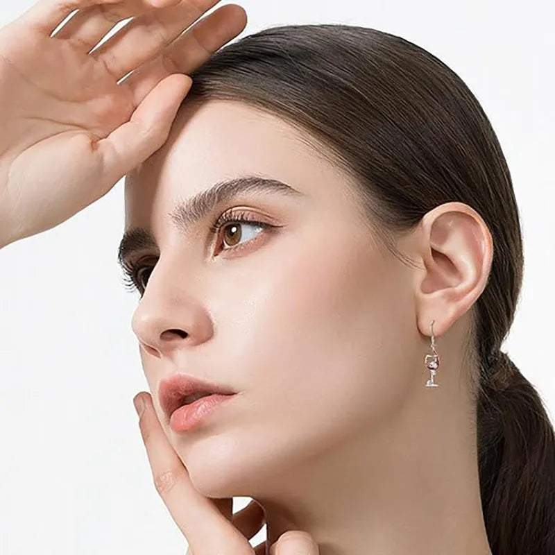 A pair of silver-toned drop earrings featuring a detailed geometry skull design combined with a wine glass shape.