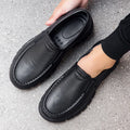 Men's black and brown slip-on work shoes with a waterproof platform and mid-top design.