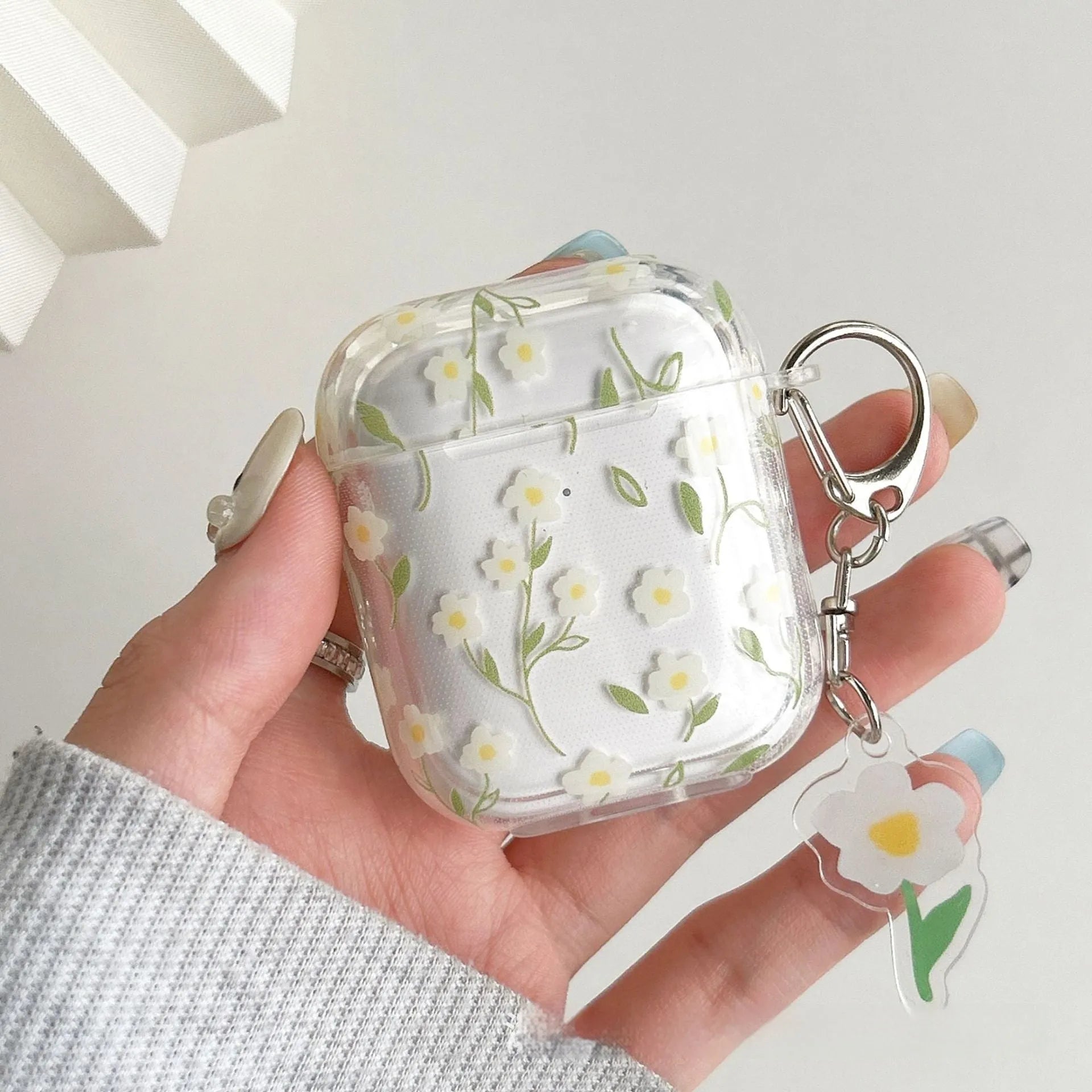 White floral pattern clear TPU protective case for Apple AirPods on a charging case.