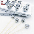 Small glass mirrored disco ball cake decoration attached to a thin wooden stick.