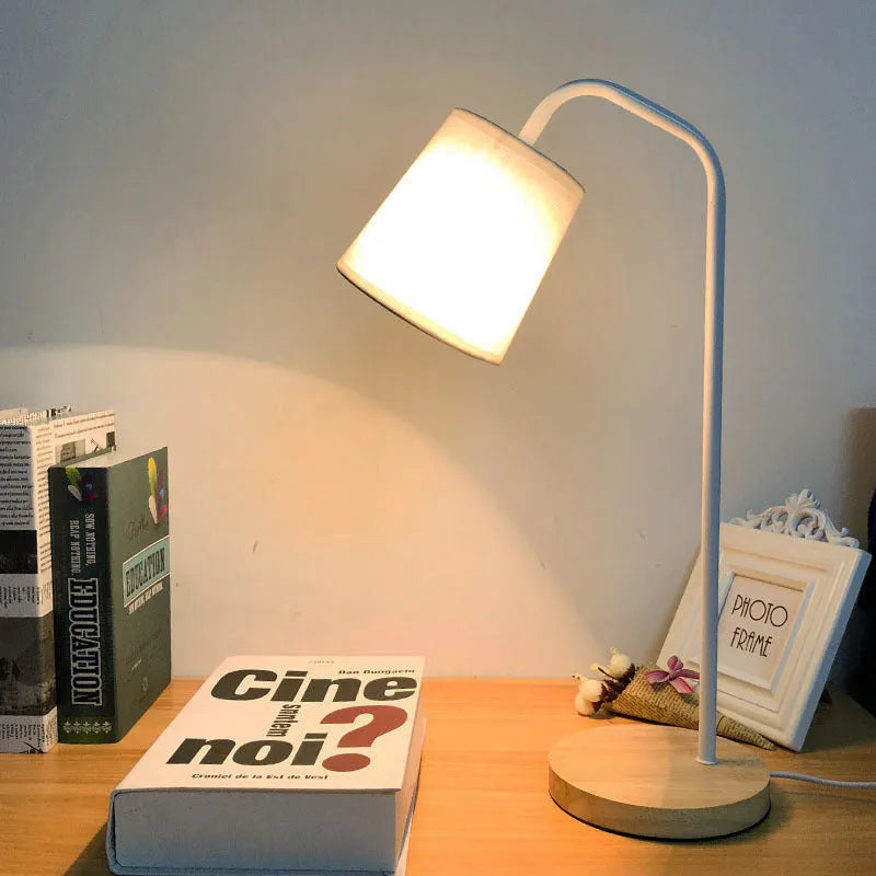 A simple modern Nordic style LED desk lamp with a dimmer switch on a desk.