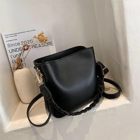 Retro style khaki crossbody bucket bag with weaving detail on the front.