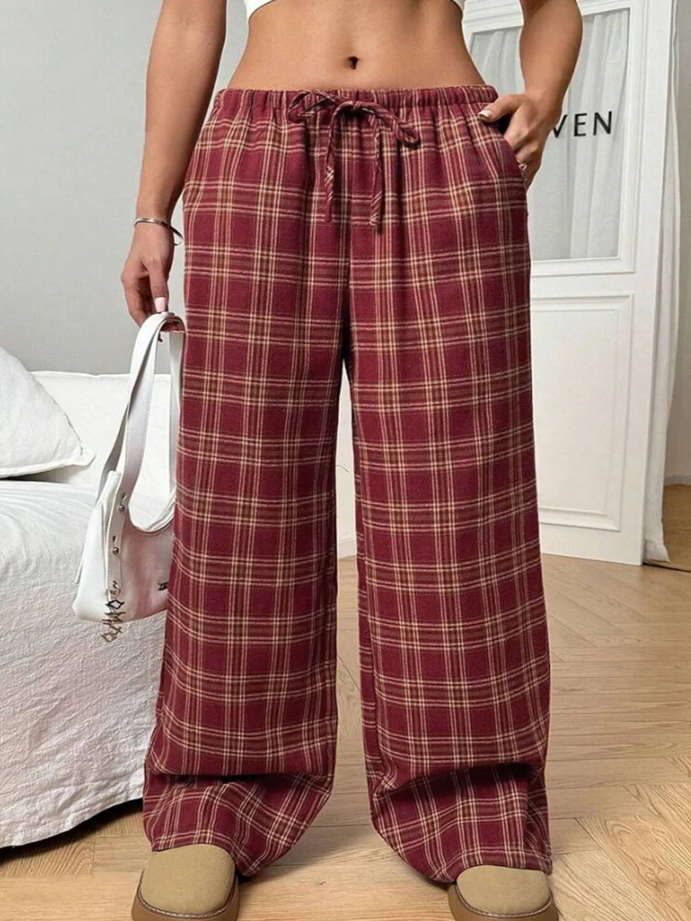Red plaid women's casual trousers with a drawstring waist and pockets on a hanger.