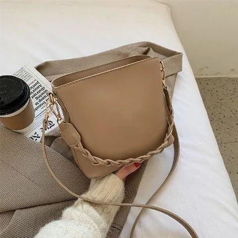 Retro style khaki crossbody bucket bag with weaving detail on the front.