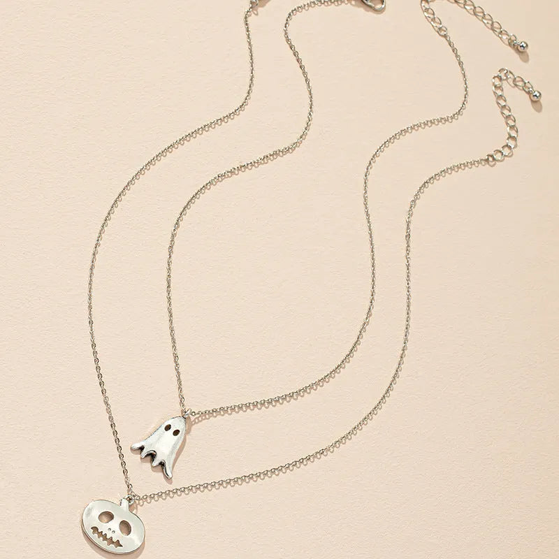 Two silver alloy pendant necklaces: one cartoon pumpkin and one cartoon ghost on a light background