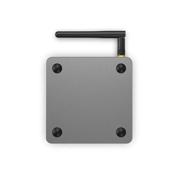 Android smart TV set-top box with voice remote control on a wooden table next to a television.