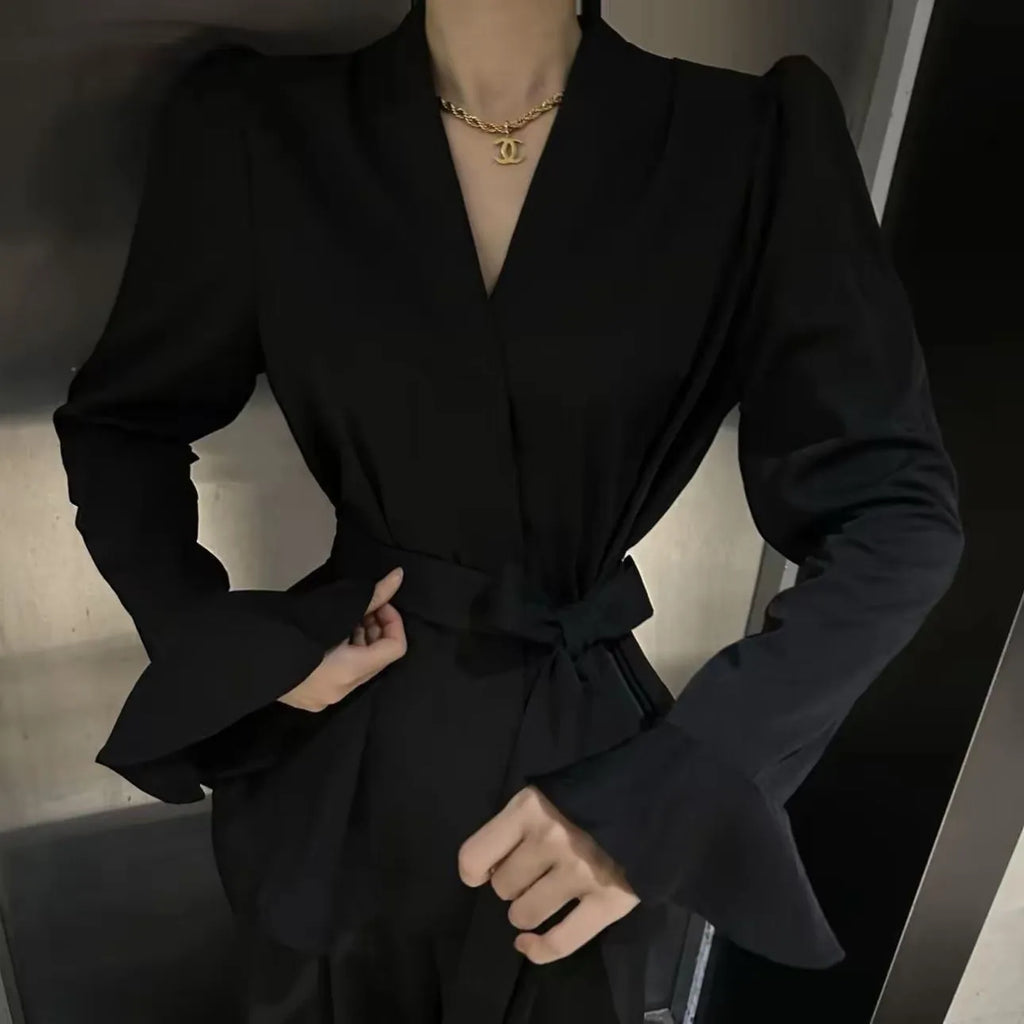 A woman wearing a black French-style shirt with an irregular collar and long bell sleeves.