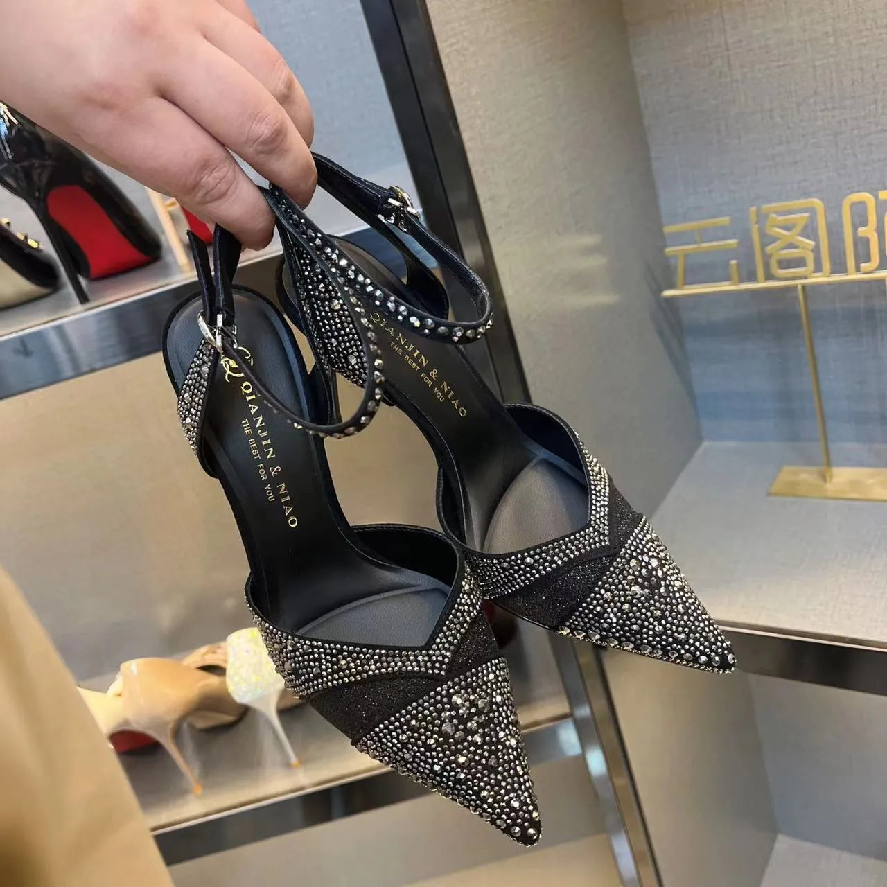Women's silver and black hollow stiletto high heels with pointed toe and red sole on a plain background.