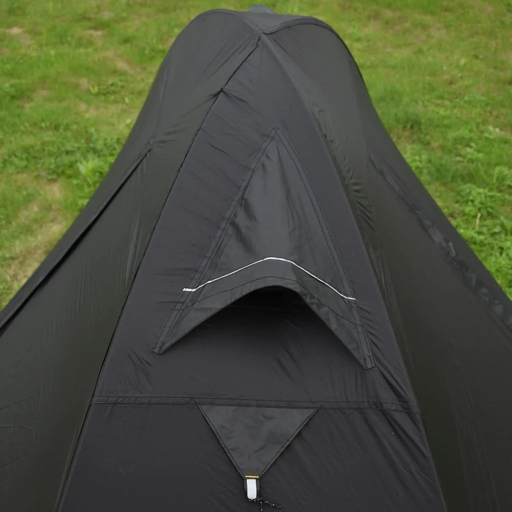 Red single-person double-layer backpacking tent with aluminium poles pitched in a grassy field