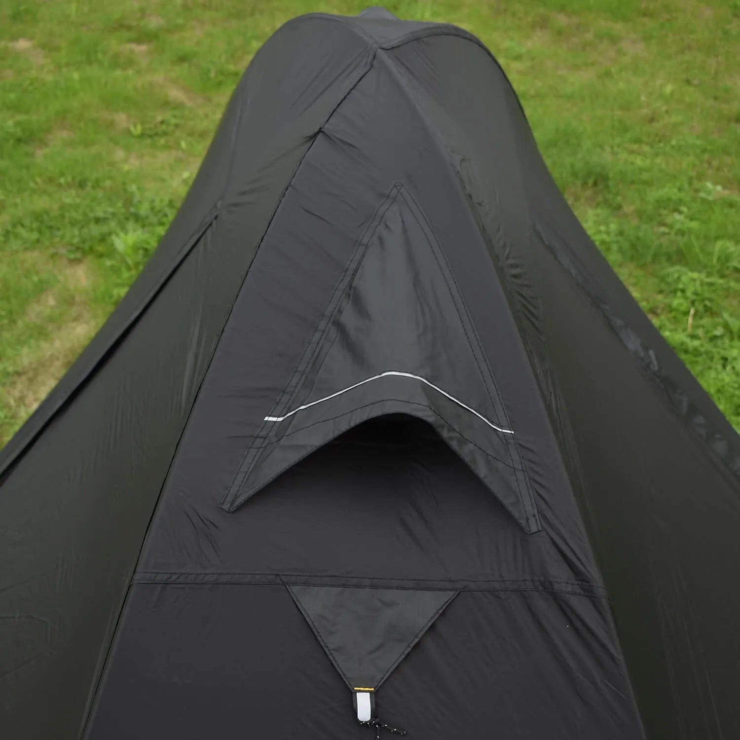 Red single-person double-layer backpacking tent with aluminium poles pitched in a grassy field