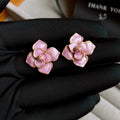 Close-up of gold plated purple flower stud earrings with iridescent oil-spot glaze on a copper base.