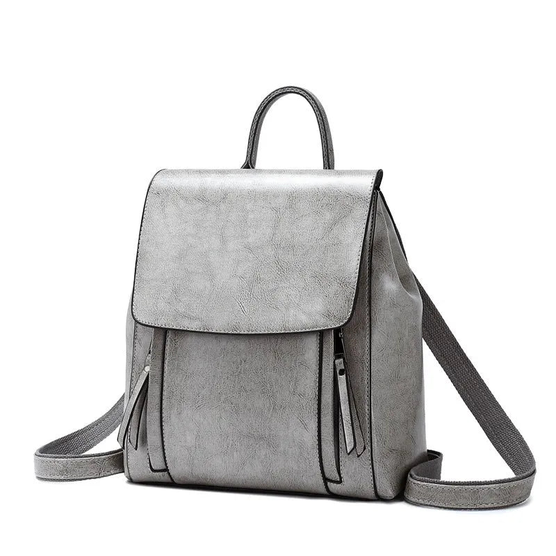 Brown oil-waxed cowhide leather women's backpack with flap closure, showing internal document pocket and stitching detail.