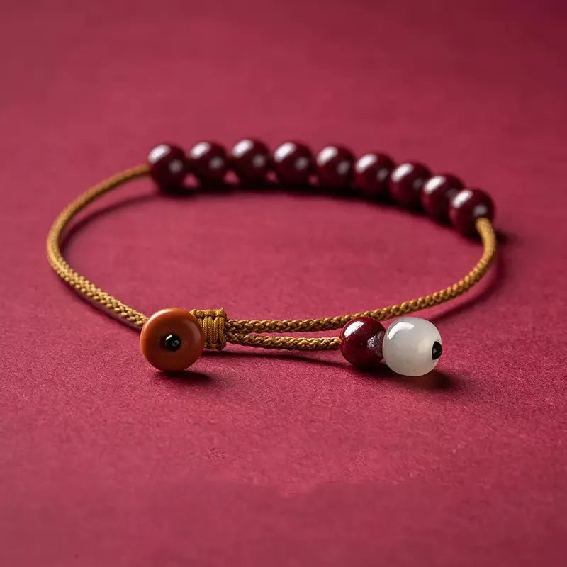 Hand-woven cinnabar and Hetian jade geometric bracelet on wrist showing natural stone textures