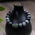 Black 10mm Eagle Eye Stone bracelet with a natural Hetian Jade Pixiu charm showing a clear water pattern.