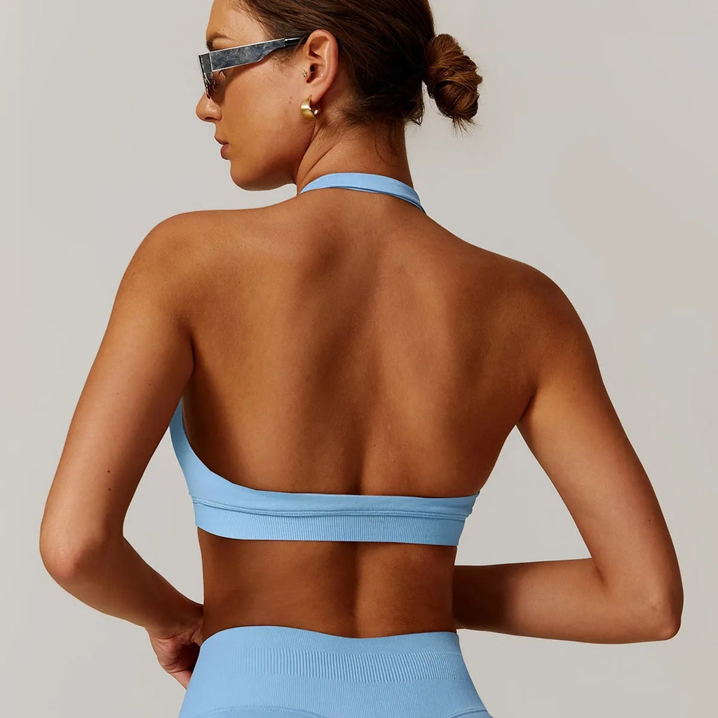 Women's black halter neck sports bra with removable padding on a grey background, showing back and front detail.