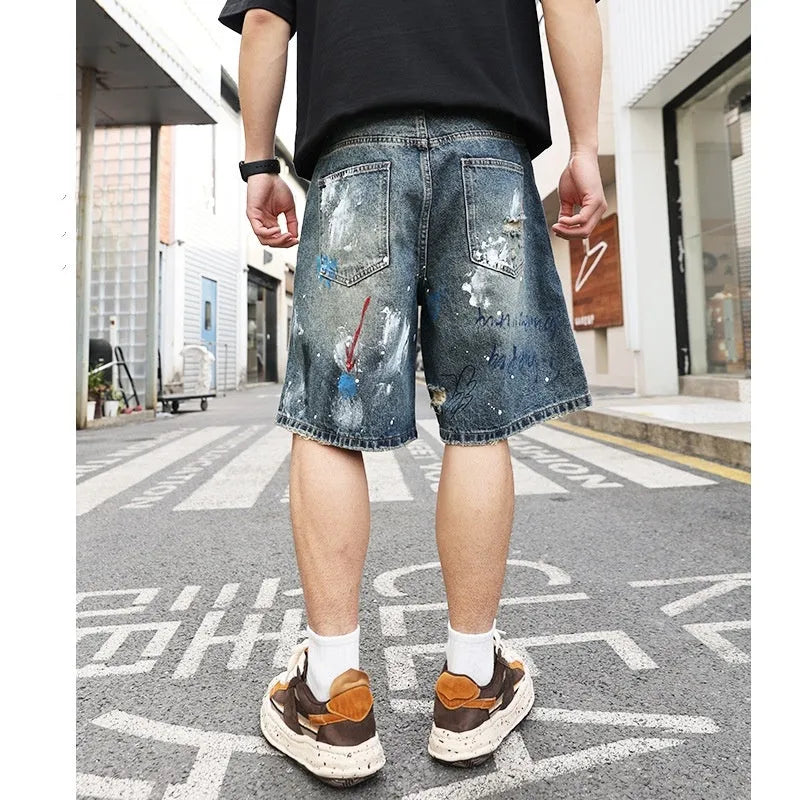 Men's blue ripped jeans shorts with straight leg cut, zipper fly, and graffiti detailing