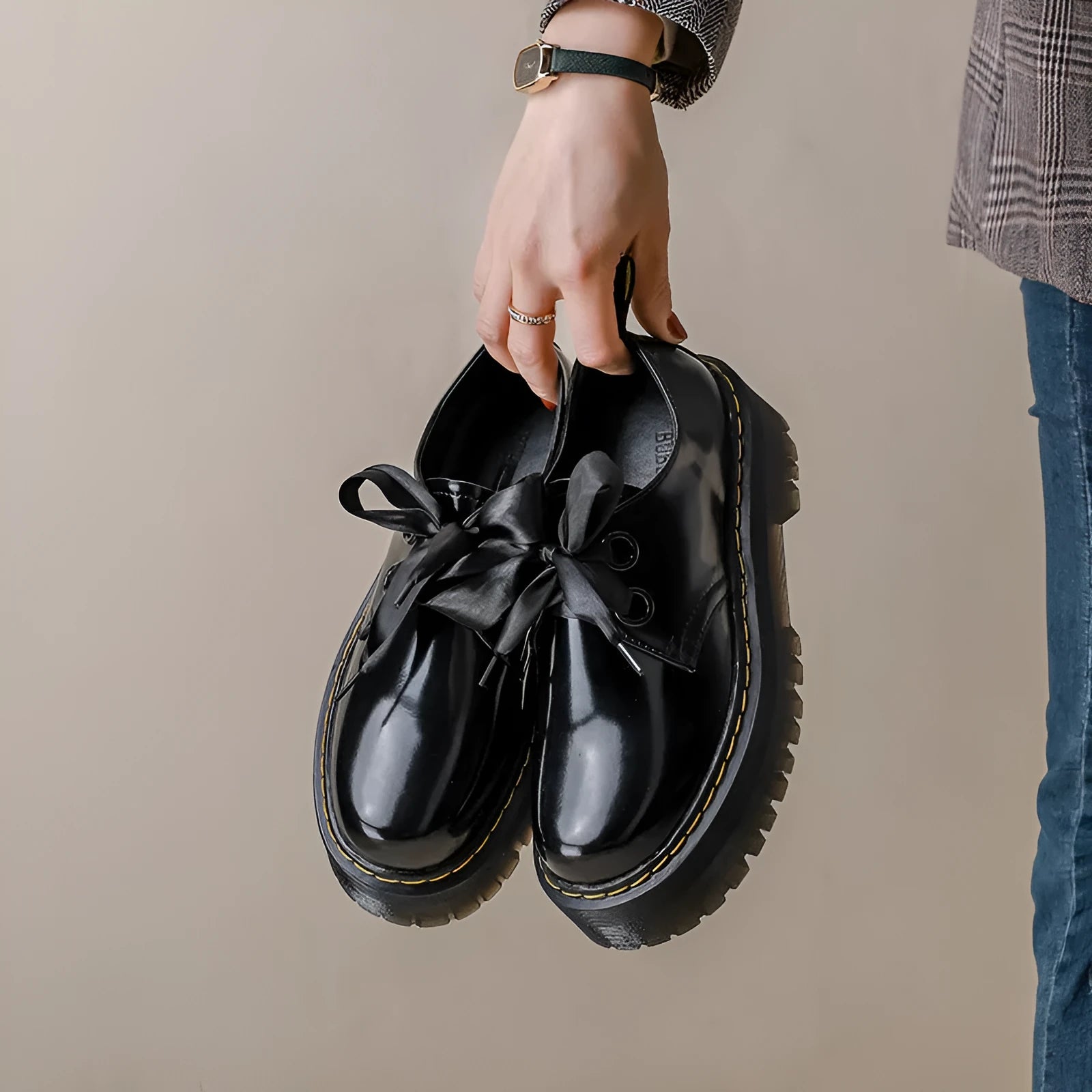 Women's black leather shoes with a thick sole, cross straps, and ribbon laces laid flat.