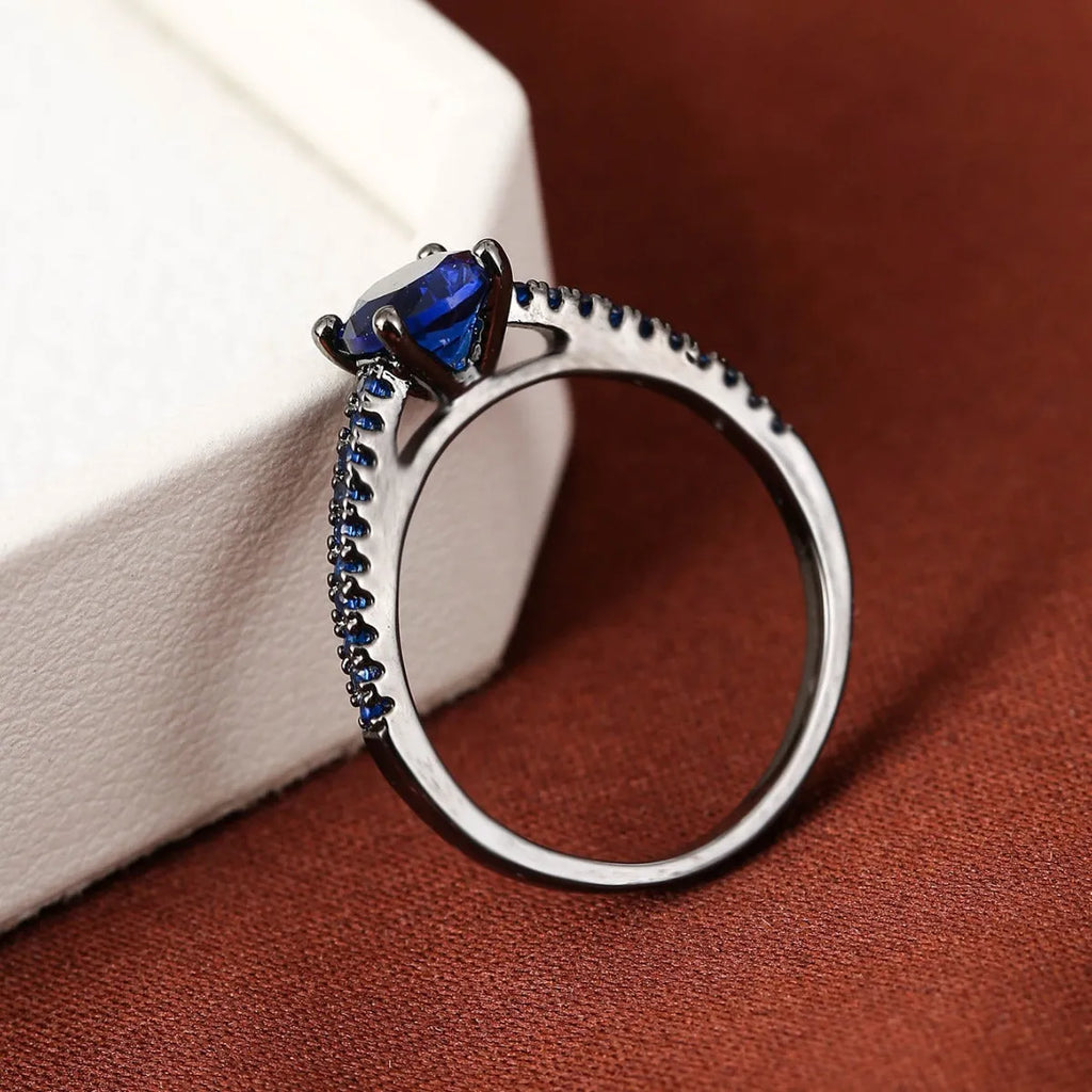 Geometric hexagonal copper ring with a zircon stone, shown in a gold rose red electroplated finish on a size 7 finger.